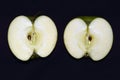 Two halves of a green juicy sliced Ã¢â¬â¹Ã¢â¬â¹apple on black background Royalty Free Stock Photo